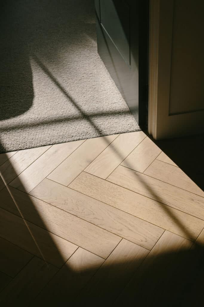 Light coloured wood herringbone floorboards in strong morning sunlight